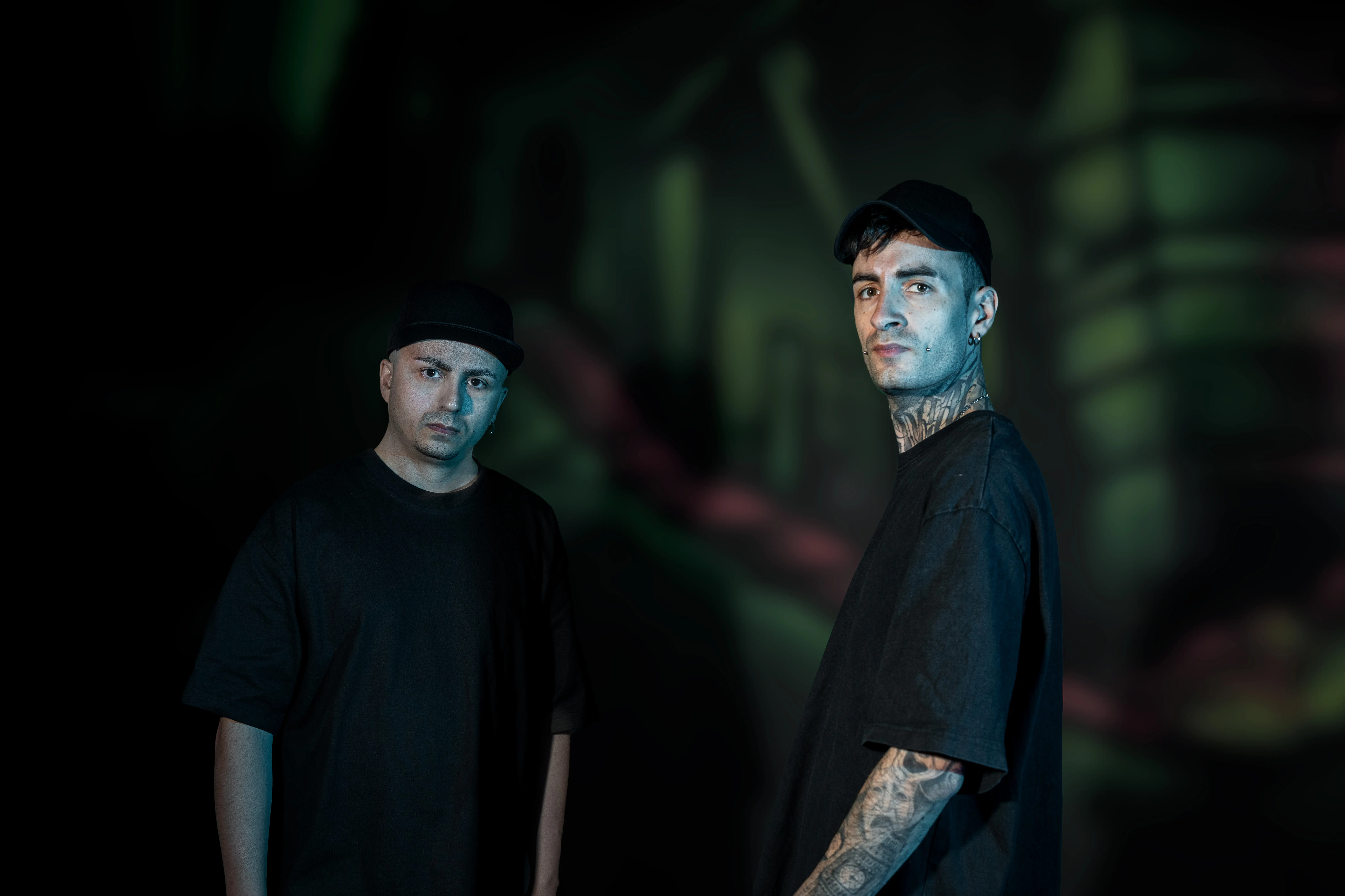 DJ Alien T and Nightshift looking at the you posed before a dark decorated background